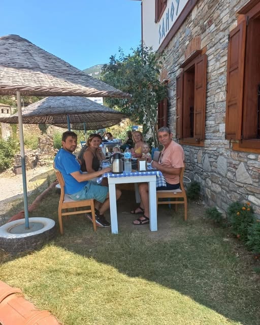 Aile grubu Samos Restaurant bahçesinde hasır şemsiye altında yemek