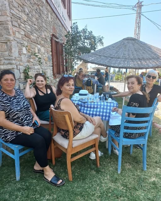 Beş kadın Samos Restaurant bahçesinde mavi sandalyeler taş bina